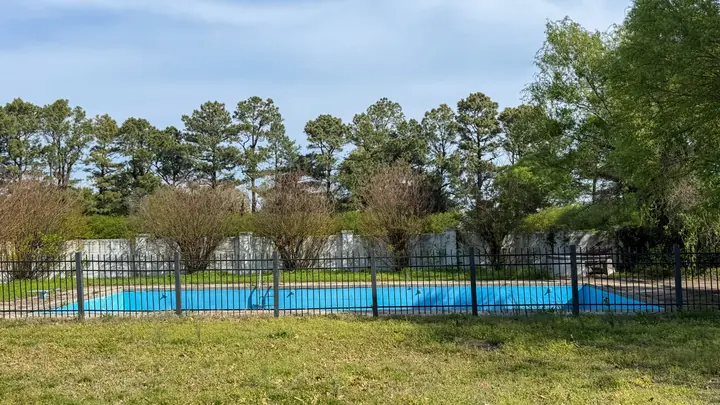 Fenced pool area framed by greenery.