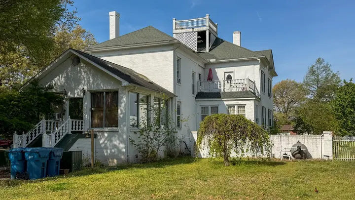 Rear view showcasing porches, balcony, and brick exterior.
