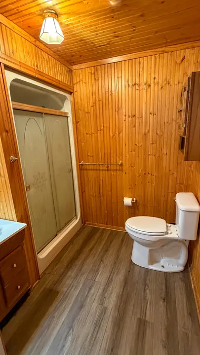 Bathroom with wood paneling and shower.
